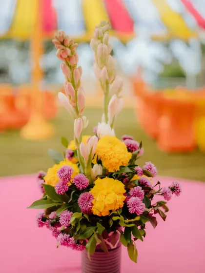 A close-up of a floral centrepiece from a Haldi event, featuring yellow marigolds, purple statice, and white tuberoses. These small details add to the overall richness and colour of the decor.