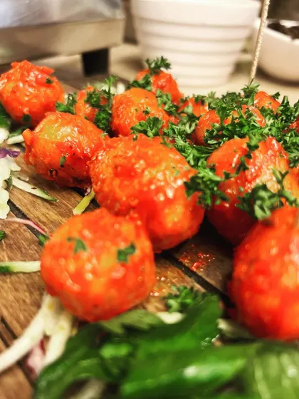 These bright red appetizer balls are seasoned and garnished with fresh parsley. Their vibrant color makes them a visually striking addition to any platter.