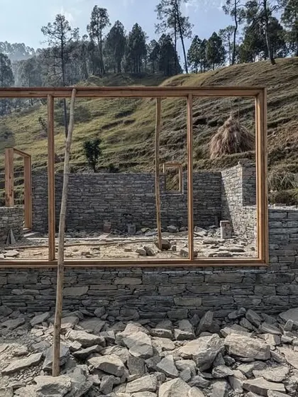 The foundation of a guesthouse is laid with local stone, with the wooden frames for the windows and walls ready to be erected. This image shows the very beginning of the building's journey from the ground up.