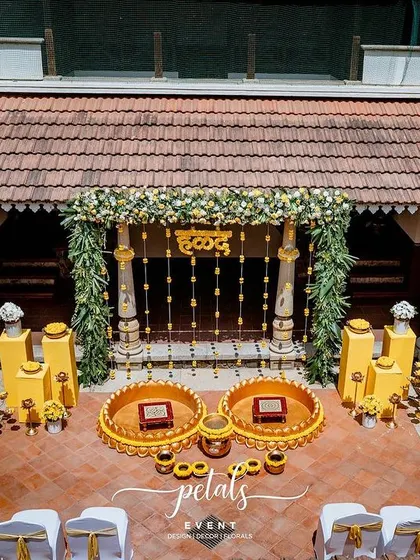 Another perspective of the stunning Haldi decor at Angana. The combination of yellow plinths, floral arrangements, and traditional props weaves a tale of festive celebration.