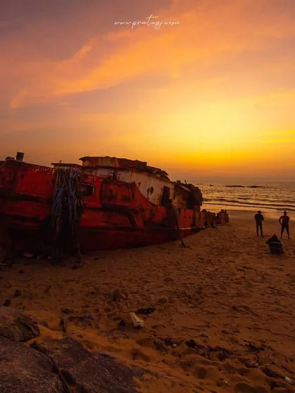 A closer look at the shipwreck at Padubidri beach during a beautiful sunset. The warm light brings out the colors and textures of the rusted vessel against the sand.