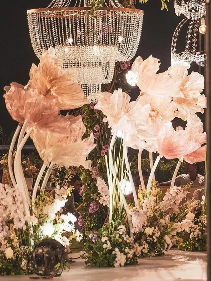 As evening fell, the mandap transformed. The warm lighting highlighted the texture of the large paper flowers and the sparkle of the hanging crystal chandeliers, creating a magical atmosphere for the nighttime ceremony.