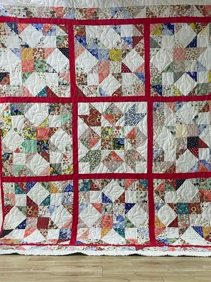 A scrappy star quilt with a bold red lattice separating the blocks.