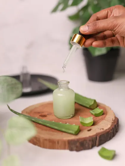 A DIY aloe vera serum shot. The image includes fresh aloe leaves and a wooden slice to emphasize the natural, homemade quality of the skincare recipe.