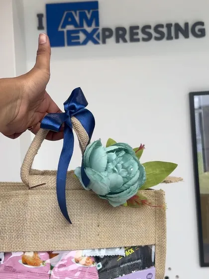 A close-up of a corporate gift bag for an event at American Express. The jute bag is decorated with a flower and ribbon that match the company's branding colors.