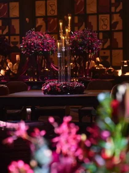A tablescape detail from the 'Raga Saga' night, showing a floral wreath centerpiece with tall glass candle holders.