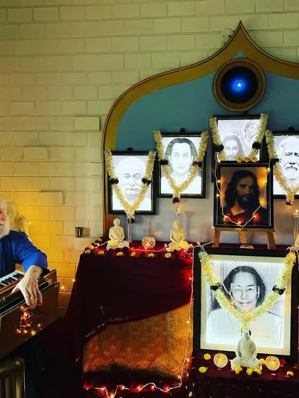 A moment of deep concentration and devotion as Nayaswami Haridas leads a chant in front of our altar. The combination of music, sacred imagery, and shared intention creates a powerful spiritual vibration.