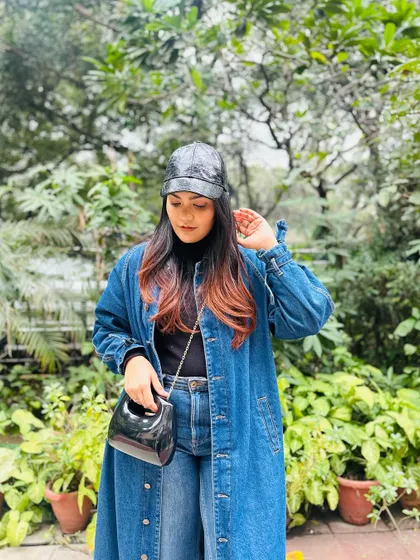 A detail shot showing the black patent bag and cap, which add a different texture to the all-denim outfit.