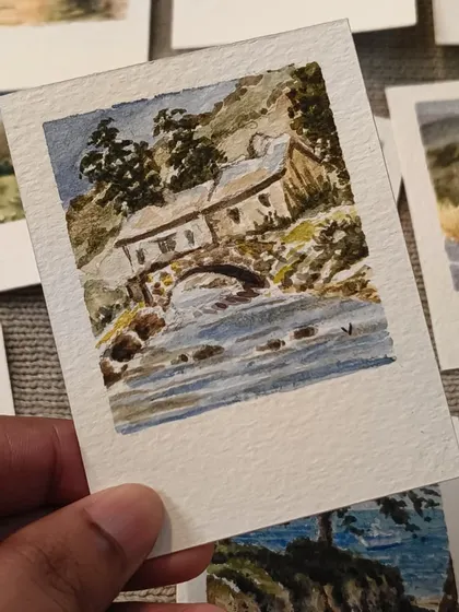 A rustic stone bridge over a flowing river, captured in this detailed mini watercolor. I focused on the texture of the old house and the movement of the water to bring this countryside scene to life.
