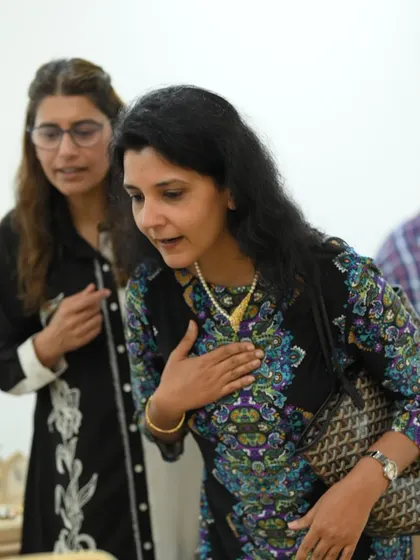 The joy of finding the one. A guest expresses her delight while trying on a classic pearl necklace, assisted by a friend at one of our Delhi showcases.