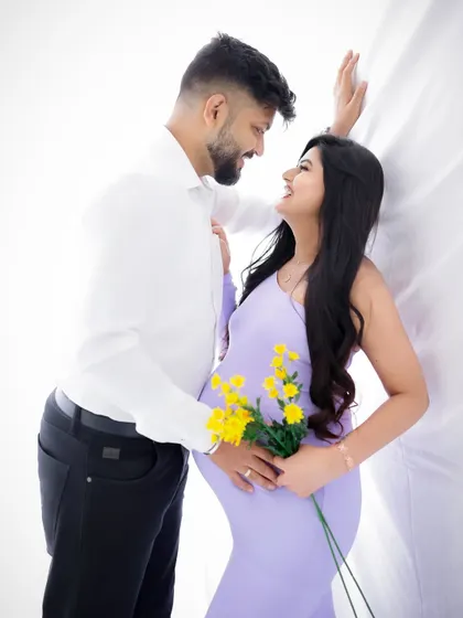 A sweet and playful couple's portrait. The mom-to-be holds a bouquet of yellow flowers, adding a pop of color to this happy scene.