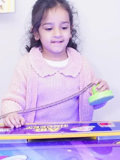 A young girl focuses on her next move in a game of air hockey.