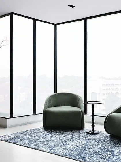 A serene corner with floor-to-ceiling windows, where two comfortable chairs create a perfect spot for a quiet conversation with a panoramic view.