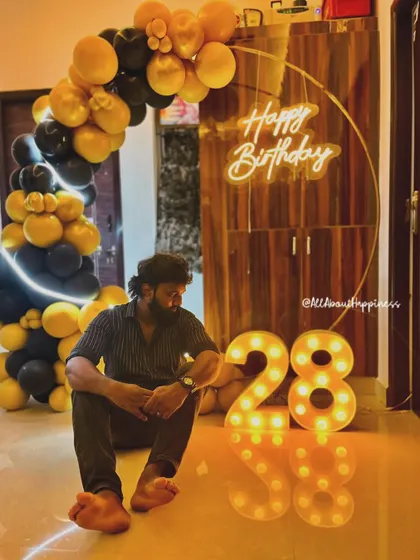 A client enjoying his 28th birthday setup. The circular backdrop with a neon sign and a black and yellow balloon arch creates a bold and modern look.