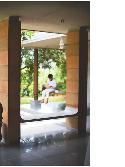 A quiet moment on the 'Jagli' of the "Aamra" house. The design incorporates many such pause points, using built-in seating and framed views to encourage slowness and a deeper connection with the serene environment.