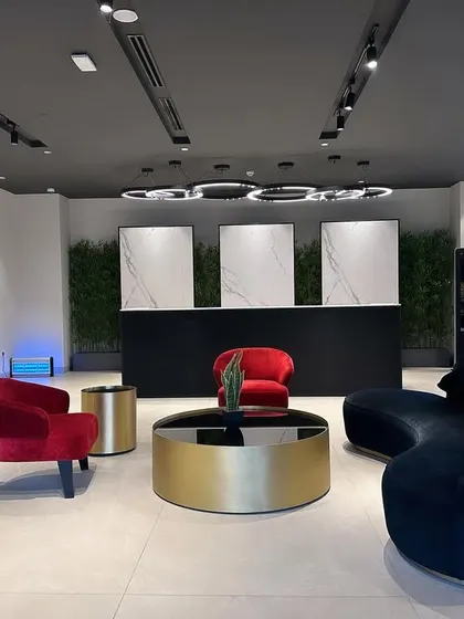 The waiting lounge at the ALP Overseas Experience Center in Kota combines comfort with high-end design. I used bold jewel tones in the velvet furniture, including a curved black sofa and red armchairs, set against a modern backdrop of marble panels and a living green wall.