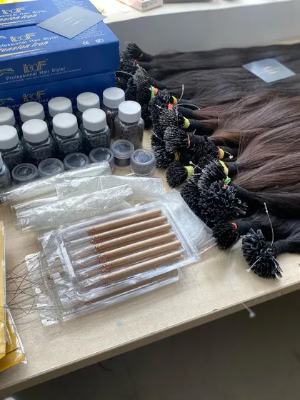 A complete set of our hair extension tools and supplies laid out on a table. We provide everything salons need, from hair bundles and tips to application tools and micro beads, all available for bulk purchase.