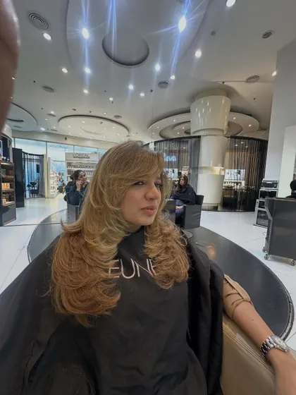 A side view of the face-framing blonde layered cut. You can see how the layers are cut to feather away from the face, creating softness and movement.