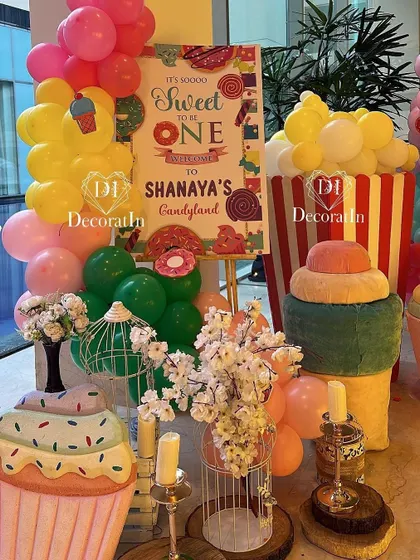 The welcome area for the Candyland party, featuring the sign, giant cupcake props, and floral arrangements.