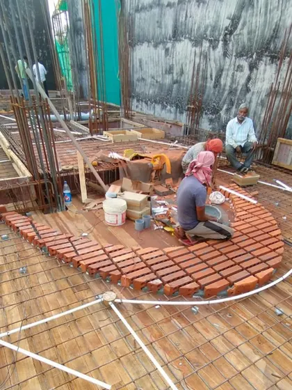 The team works to complete the elliptical brick pattern for the slab. This behind-the-scenes view shows the collaborative effort involved in executing complex architectural details.
