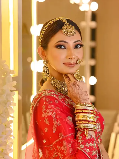 A stunning traditional bride. Her hair is styled in a neat bun with a matha patti, and the look is completed with a long, accessorized braid, perfect for a classic wedding ceremony.