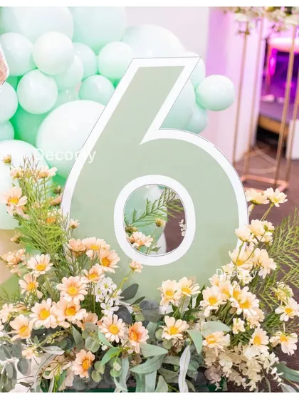 A stylish number '6' prop surrounded by flowers, part of the decor for the Labubu-themed birthday.