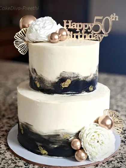 An abstract black and gold design for a 50th birthday celebration. This two-tier vanilla and butterscotch cake uses a modern, artistic buttercream technique, proving that milestone cakes can be both elegant and contemporary.