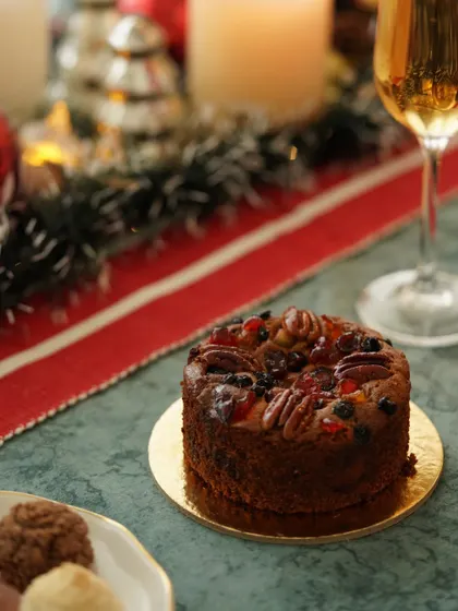 A non-alcoholic plum cake, rich with fruits and nuts, styled on a festive table for an inclusive holiday celebration.