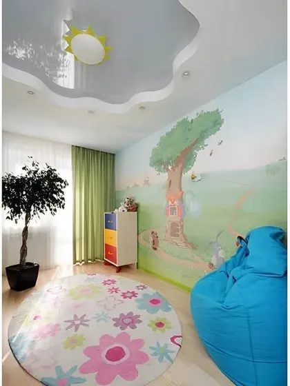 A simple and sweet kids' room with a painted wall mural and a flower-shaped false ceiling design. The beanbag chair offers a comfy spot for reading or relaxing.