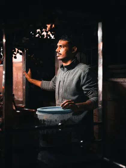 The play of light and shadow in a dimly lit street stall creates a naturally dramatic scene. This candid shot of a vendor is an example of my low-light street photography, finding cinematic moments in everyday settings.