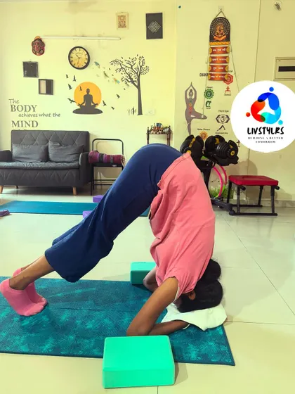 A client practices Sirsasana (Headstand) with the support of blocks and a wall. This is a safe way to build the strength and confidence needed for inversions.