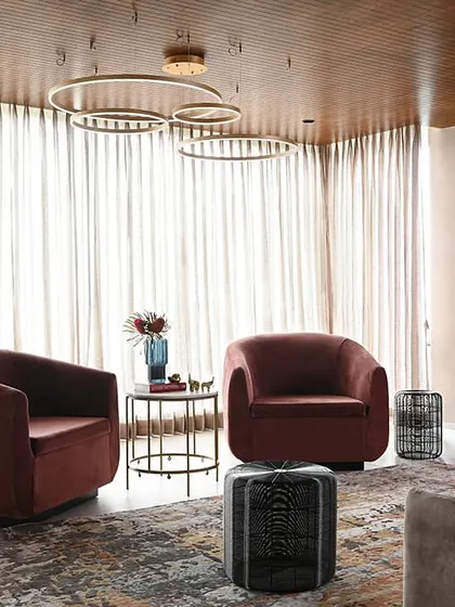 This ante-room serves as a private lounge for VIP meetings. The design uses plush, curved armchairs, a rich area rug, and circular pendant lights to create a soft, comfortable, and luxurious atmosphere.