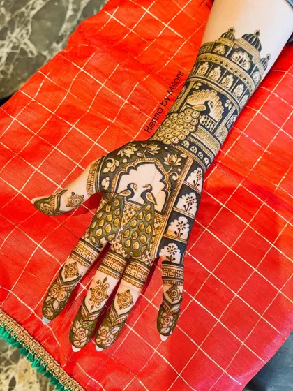 For brides who love detailed work, this design features majestic peacocks within ornate arches, with palace-inspired patterns on the forearm.