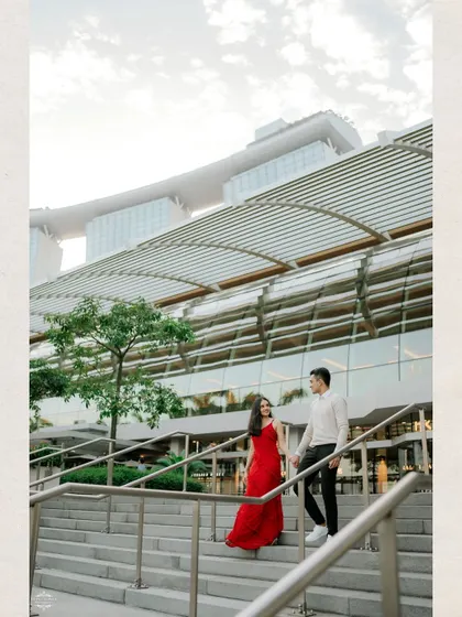 A stylish portrait of a couple on a grand staircase with Singapore's Marina Bay Sands in the background. The architecture adds a sense of scale and drama to the shot.