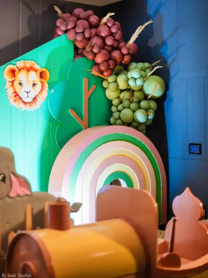 A detailed shot of the boho jungle decor, featuring a pastel rainbow, a lion cutout, and balloon arrangements that look like grape vines, adding a unique twist to the theme.