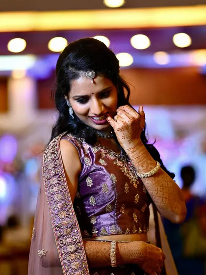 Another candid portrait of the bride, capturing her natural smile and the intricate details of her reception lehenga and henna.