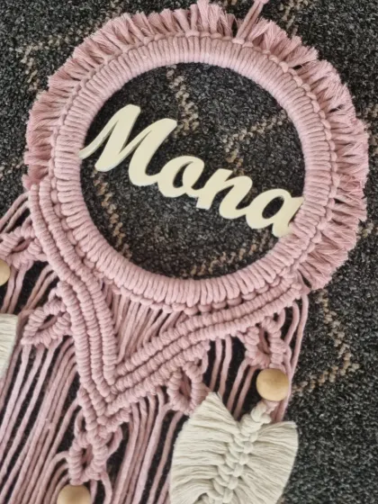 A closer look at the 'Mona' name hanging, showing the detail in the macrame knots and the elegant script of the name.