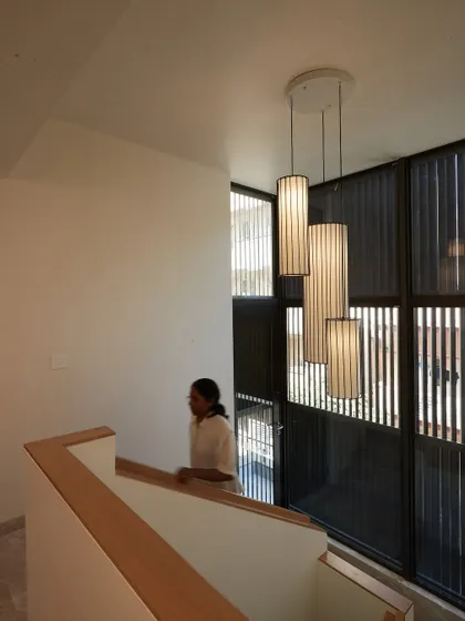 The light fixture acts as a focal point within the vertical volume of the staircase.