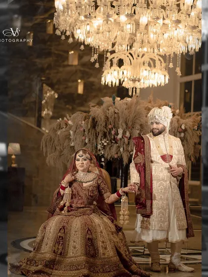 A beautiful wedding portrait of the couple holding hands, set against a backdrop of luxurious decor and a stunning chandelier.