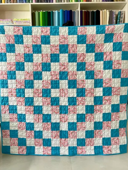 A "Trip Around the World" quilt in cheerful pink and teal, featuring a fun rainbow print. This simple checkerboard design is a classic for a reason.