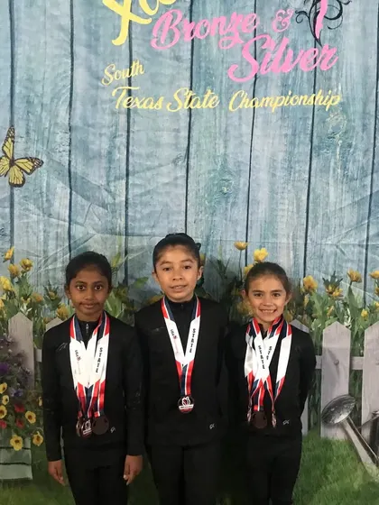 Three of our Bronze athletes with their medals in front of the South Texas State Championship backdrop.