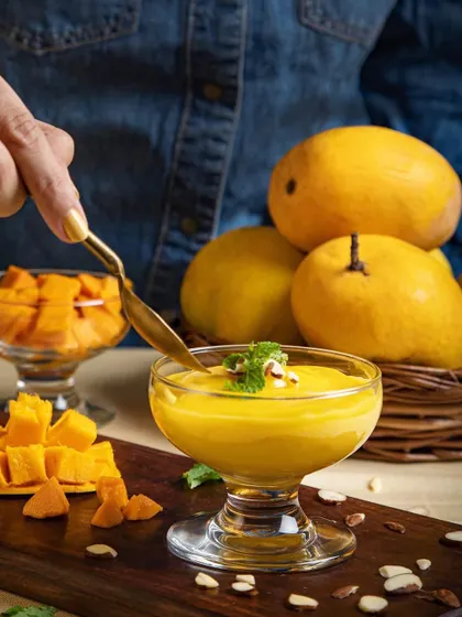 Capturing the essence of summer with this rich mango dessert. The action of the spoon dipping in adds a dynamic, human element that invites the viewer to take a bite.