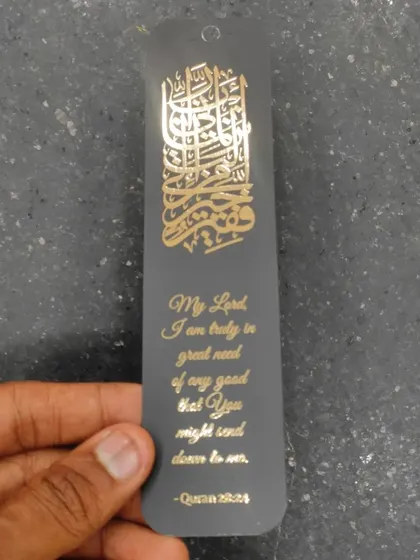 Another view of the elegant bookmark favor, highlighting the intricate gold foil calligraphy against the dark background.