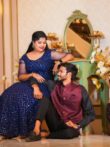 A romantic indoor shot with the couple posed near a vintage-style vanity. The warm lighting and elegant decor create a classic feel.
