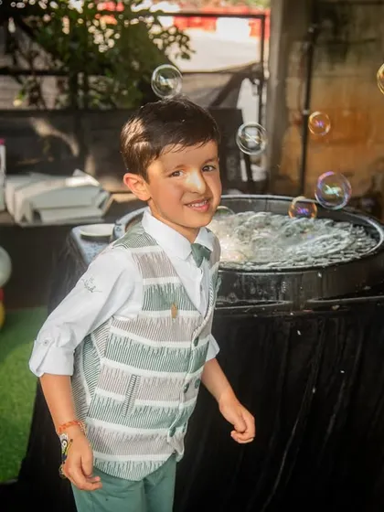 A candid shot of the birthday boy enjoying the bubble machine. The soap bubble on his nose adds a touch of humor and charm to this fun photo.