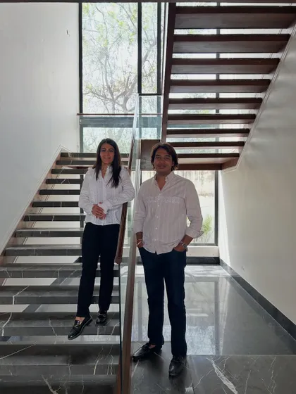 The co-founders on the modern, light-filled staircase of the 'House of Passages' project. The design features open risers and a large window that floods the space with natural light.