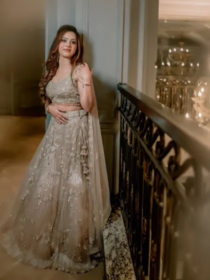 A full-length portrait of the bride in a grand hallway. The warm glow from the chandeliers and her sparkling gown create a look of pure opulence and grace.