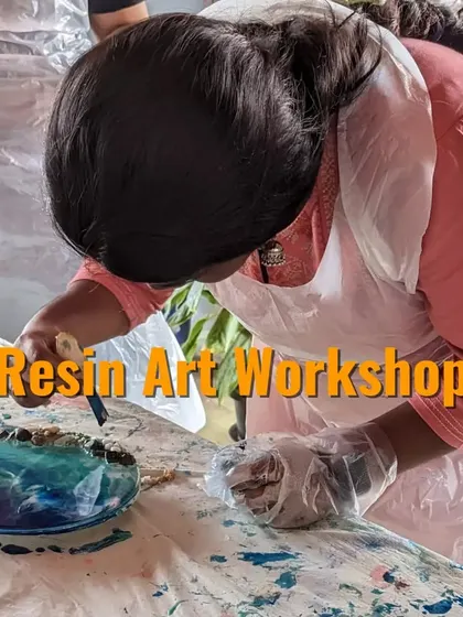 An instructor guiding a participant as she adds decorative elements to her resin beach art, ensuring she gets the perfect result.