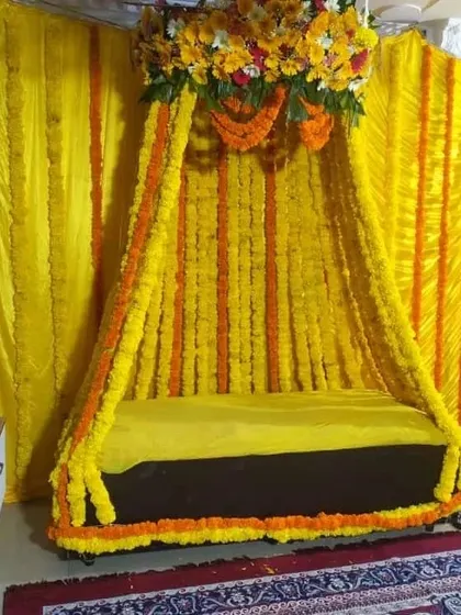 A canopy-style seating for a Haldi ceremony, created with dense strings of yellow and orange marigolds for a fully traditional look.