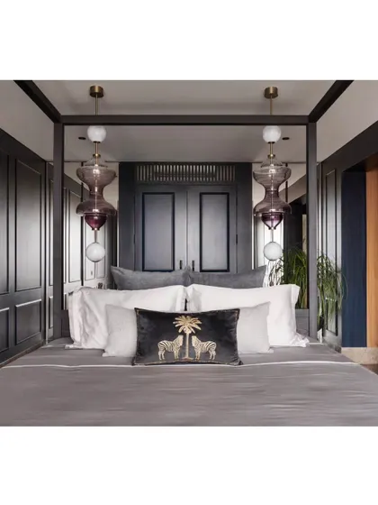 The custom four-poster bed with its integrated headboard and side tables. The statement purple glass lights add a pop of color and artistry to the moody, sophisticated space.